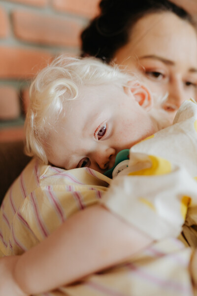 Photo d'un bébé dans les bras d'une femme, prêt à s'endormir.
