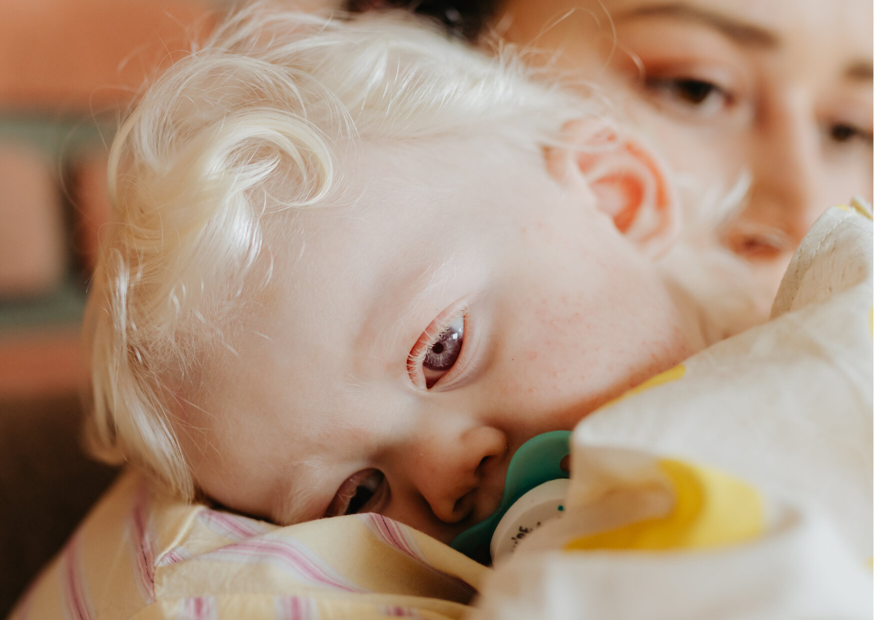 Photo d'un bébé dans les bras d'une femme, prêt à s'endormir.